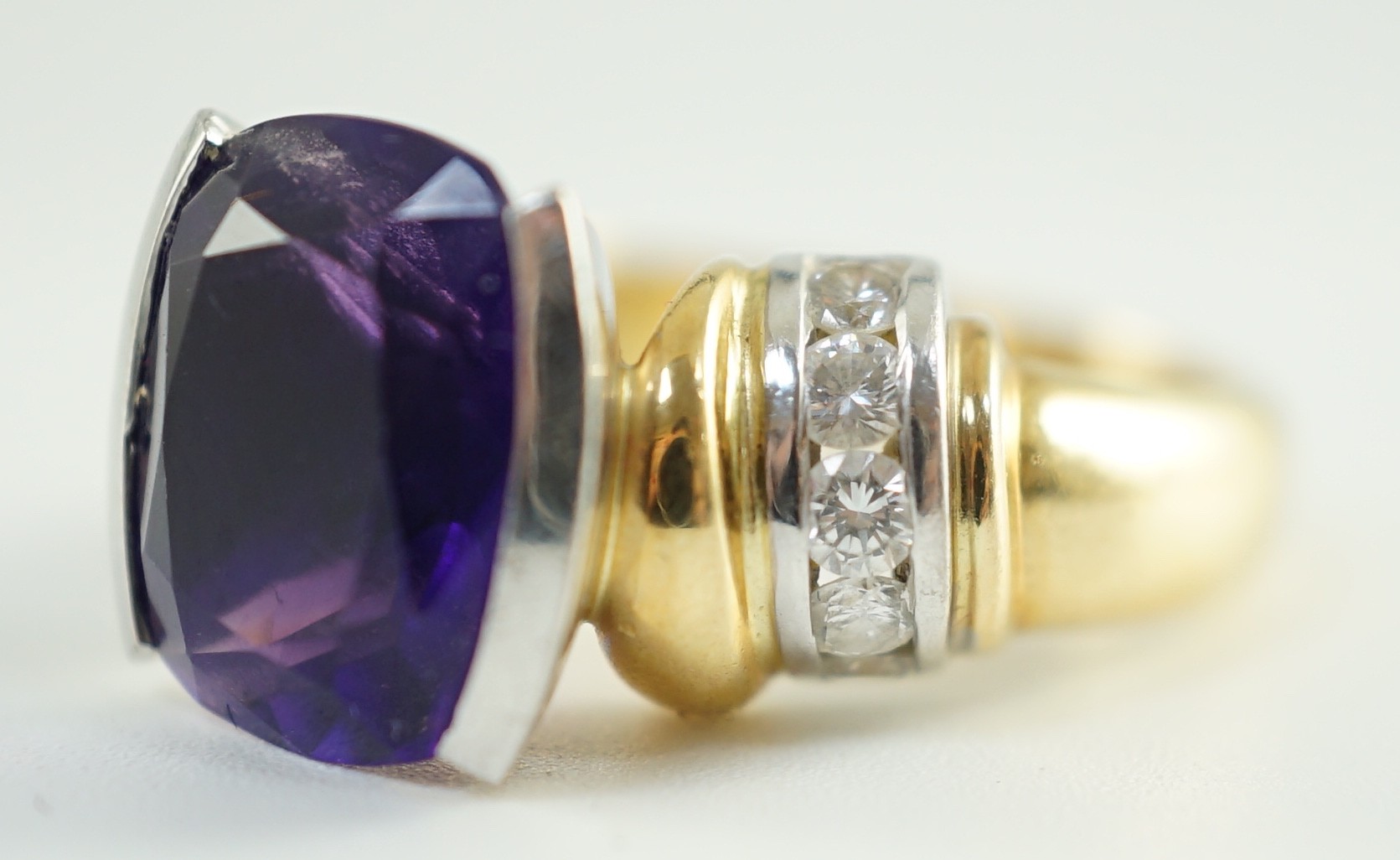 A modern 18ct gold and cushion cut amethyst set dress ring, with ten stone round cut diamond set shoulders